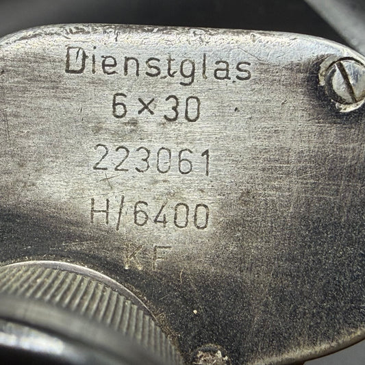 Close-up of wartime markings on German Dienstglas 6×30 binoculars, showing eso manufacturer code, serial number and H/6400 specification.