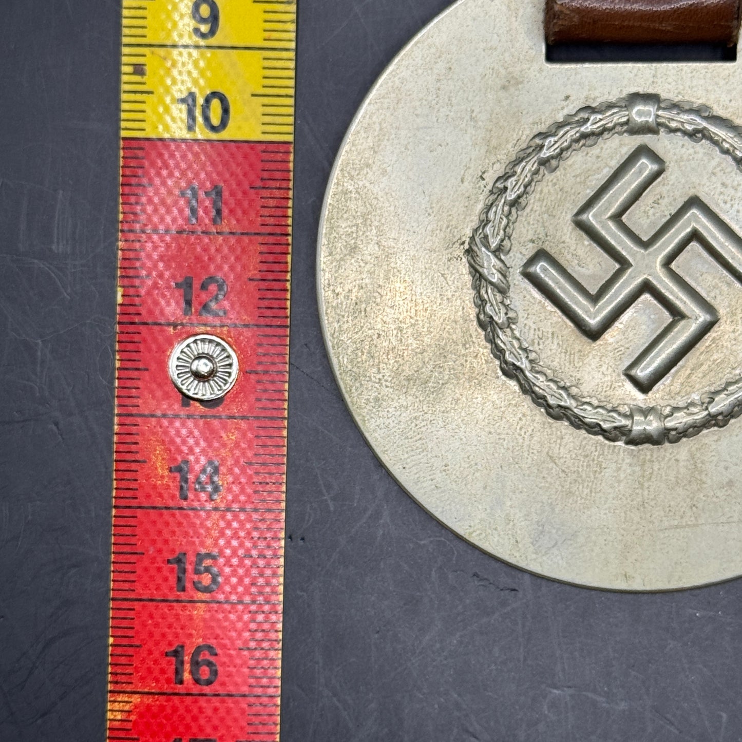 WW2 original artifact – WWII-era German metal swastika mounted on leather – interior page