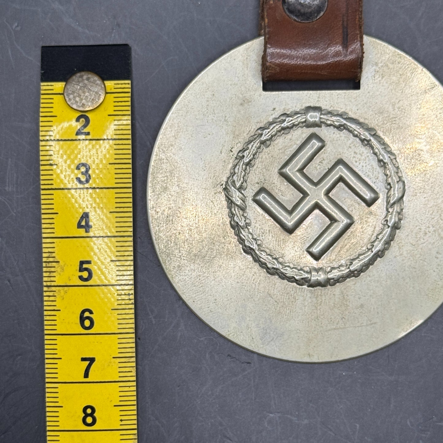 WW2 original artifact – WWII-era German metal swastika mounted on leather – interior page