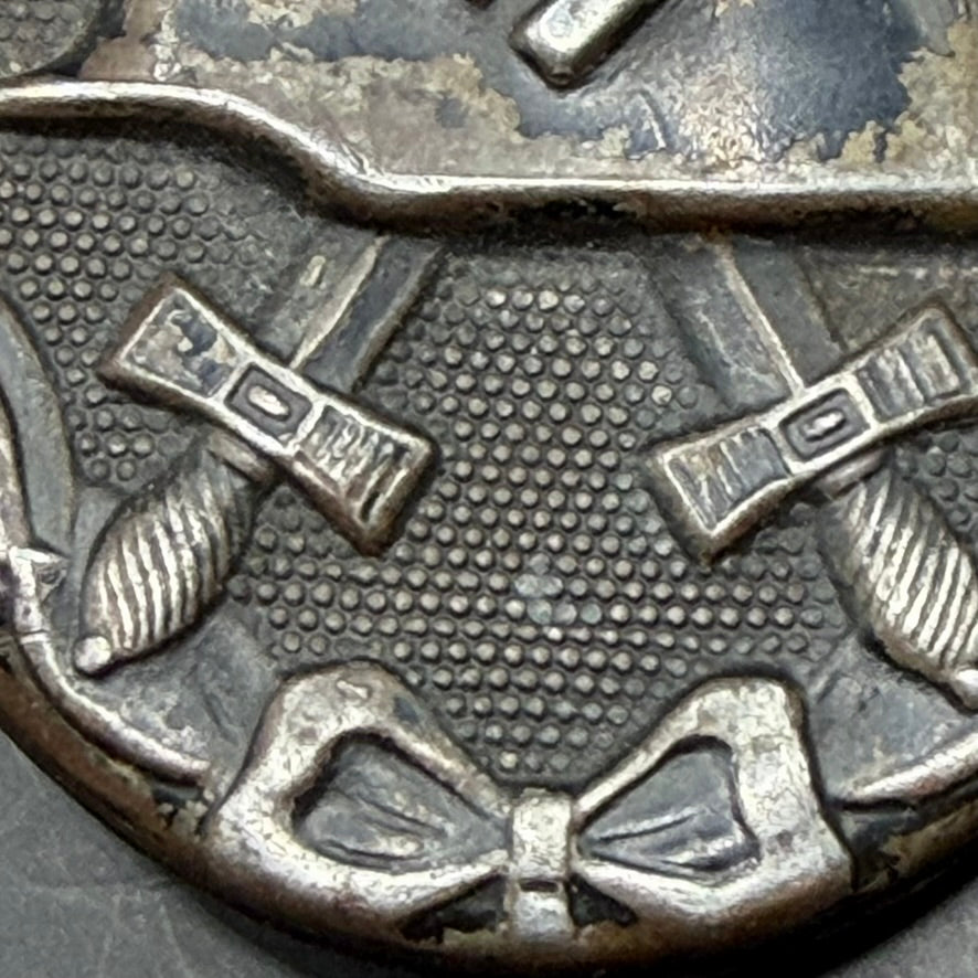 Close-up of crossed swords and textured background on WWII German zinc Wound Badge