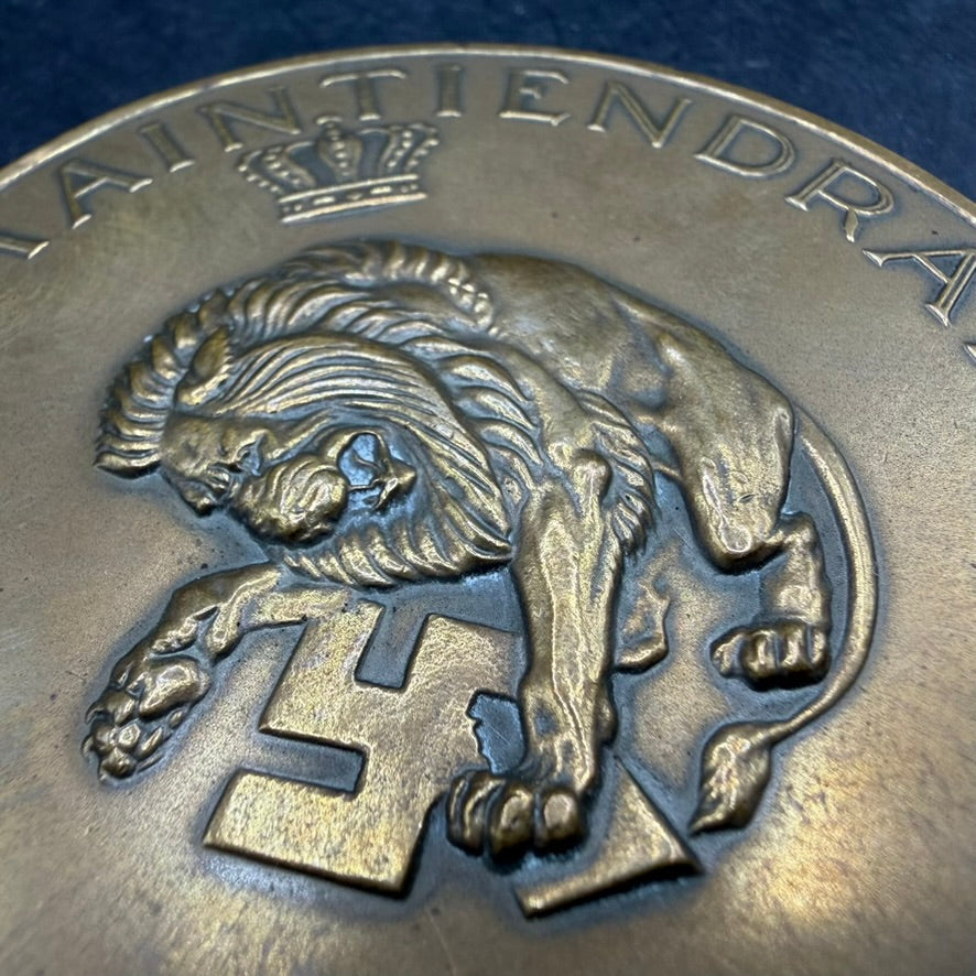 Close-up bronze liberation medal 1945, Dutch lion crushing swastika symbol beneath paw, high relief detail.