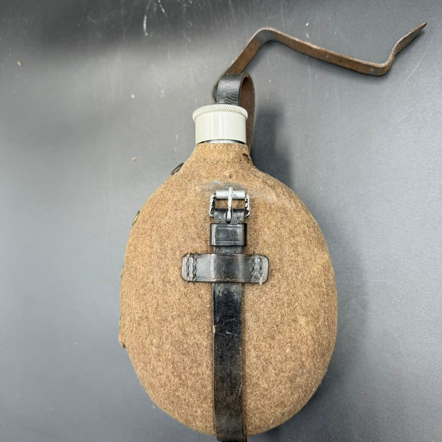 Side view of WW2 German M31 canteen with felt cover and leather strap, showing period wear