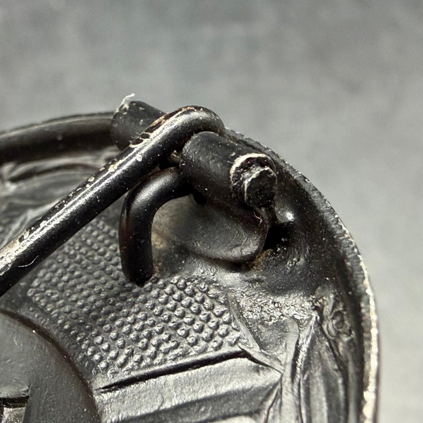 Close-up of iron oval sheet metal hinge on L/53 wound badge